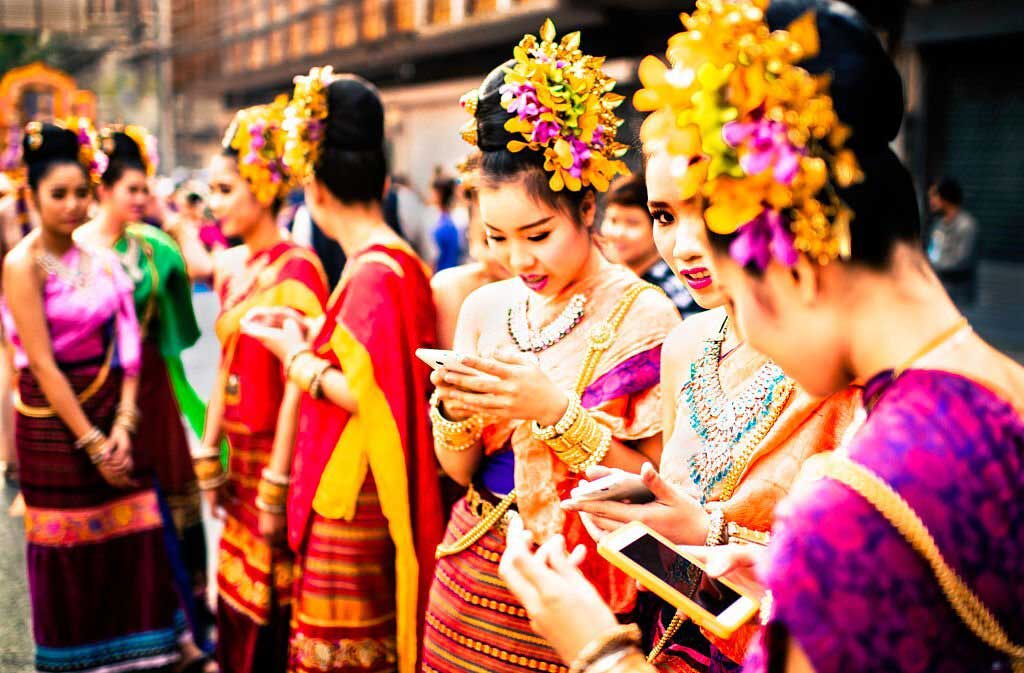Girls check their smart phones during annual flower parade in Chiang Mai